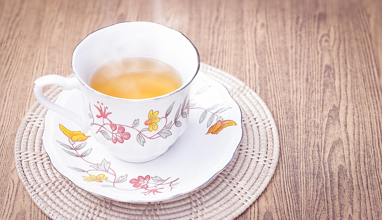 Tazza di tè fumante su un tavolo, con fette di limone e foglie di tè fresche.