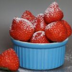 Fragole fresche su un tavolo, simbolo di rimedio naturale contro il gonfiore addominale.