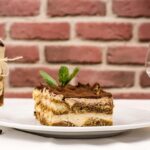 Tiramisù con crema al mascarpone, strati di savoiardi e cacao spolverato in cima.