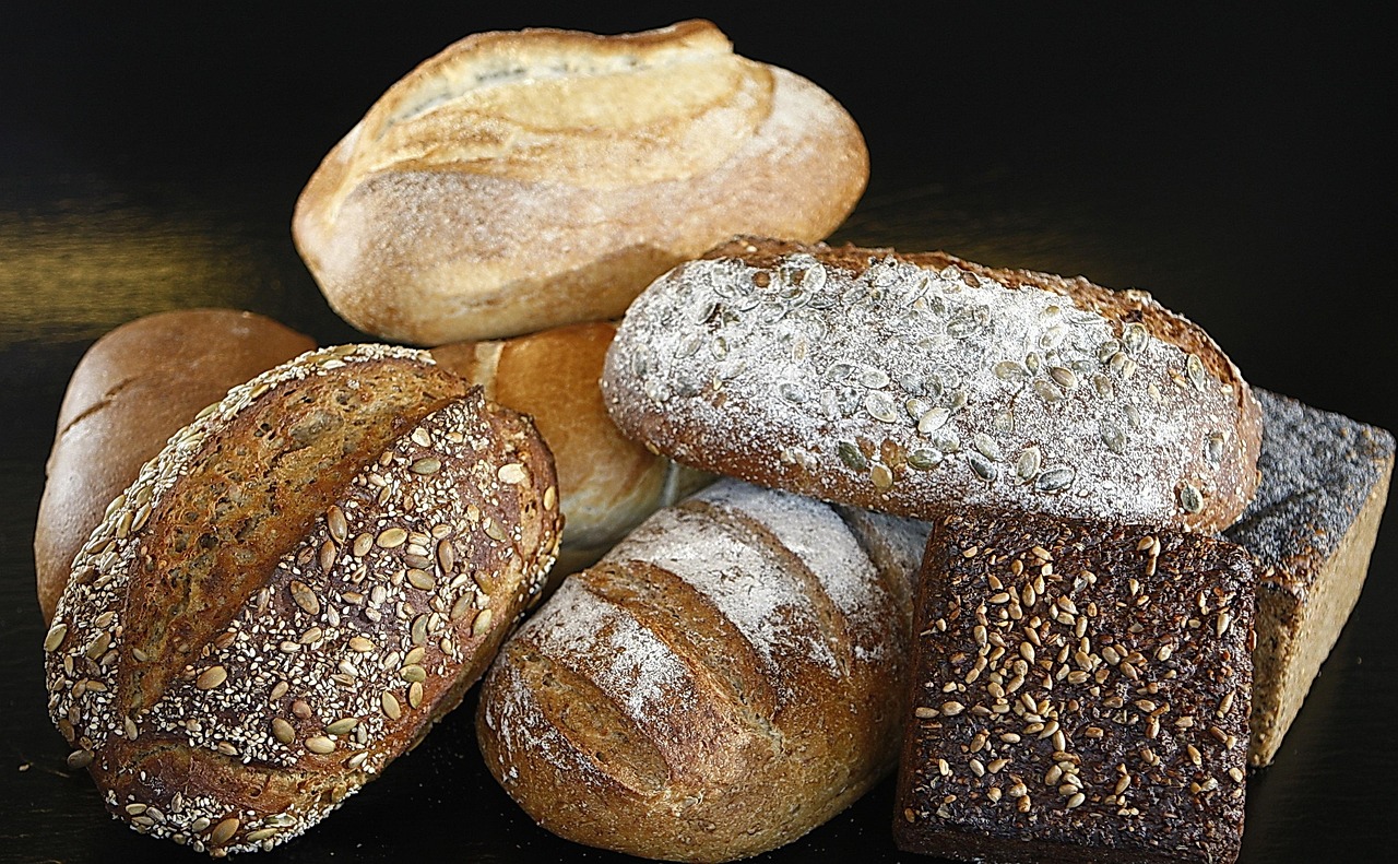 Fette di pane su un tavolo con misurini e alimenti sani, per illustrare il consumo moderato di pane.